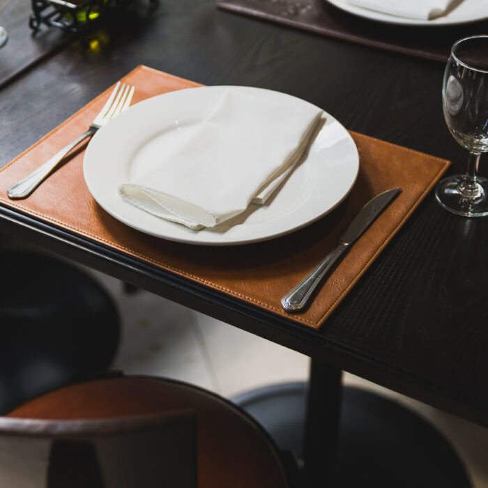 Italian dinner table with cutlery, plate, glass, napkins and naperies with salt and pepper on the table.